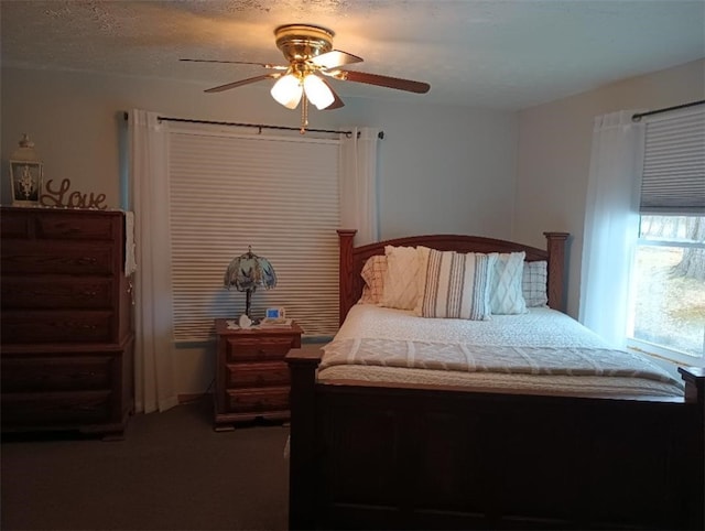 bedroom featuring dark colored carpet, a textured ceiling, and ceiling fan