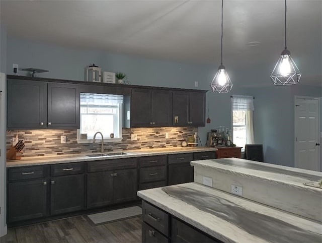 kitchen featuring sink, backsplash, plenty of natural light, and hanging light fixtures