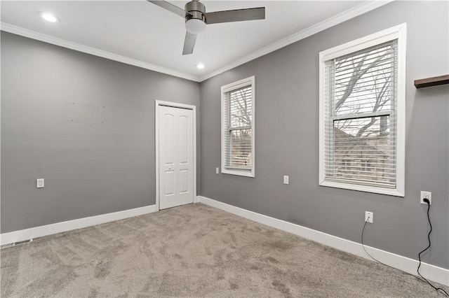 empty room featuring ceiling fan, ornamental molding, and light carpet