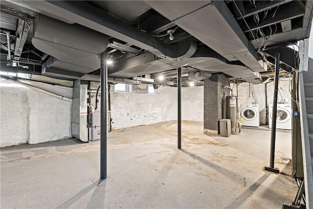 basement featuring water heater, separate washer and dryer, and heating unit