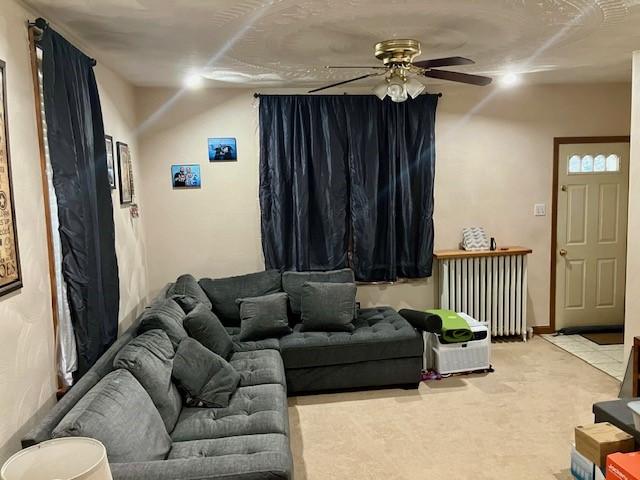 carpeted living room featuring radiator heating unit and ceiling fan