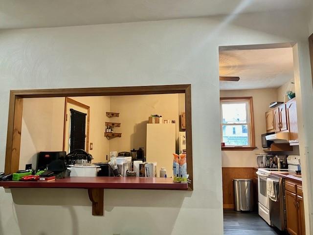 interior space featuring dark hardwood / wood-style floors, a breakfast bar area, kitchen peninsula, and white range with electric cooktop