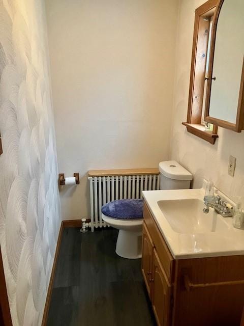 bathroom featuring vanity, radiator, hardwood / wood-style floors, and toilet