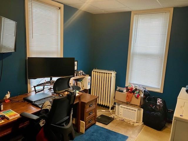 office space featuring a drop ceiling and radiator