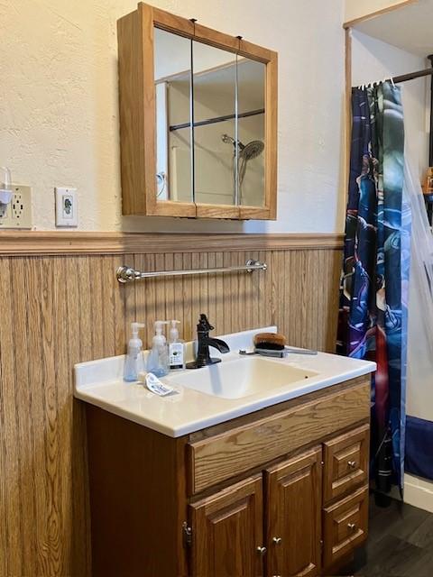 bathroom with hardwood / wood-style flooring, vanity, wooden walls, and a shower with shower curtain