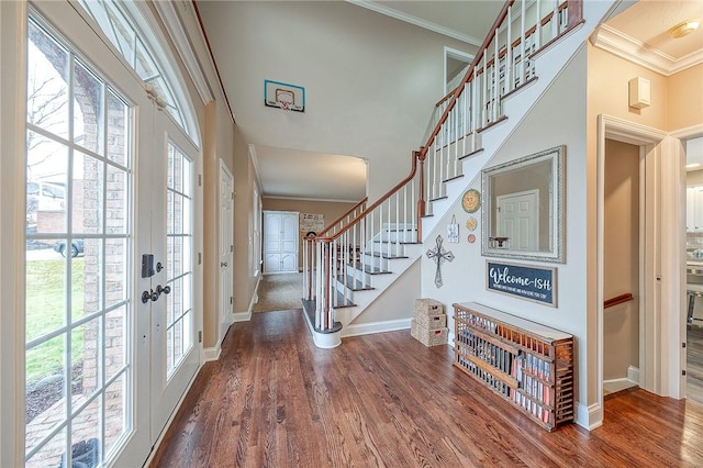 entryway with a towering ceiling, ornamental molding, and wood-type flooring