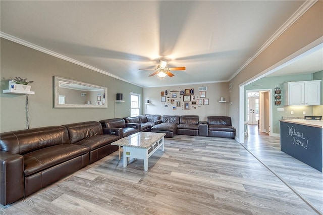 living room with ceiling fan, ornamental molding, and light hardwood / wood-style floors