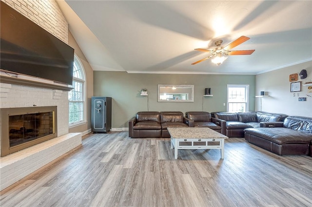 living room featuring a brick fireplace, hardwood / wood-style flooring, ornamental molding, and ceiling fan