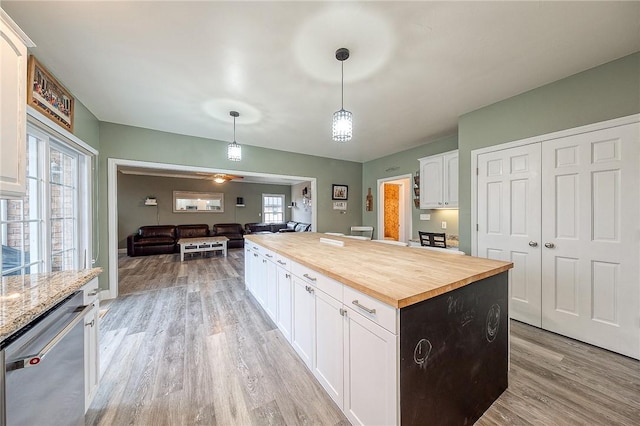 kitchen featuring pendant lighting, white cabinetry, butcher block counters, a center island, and stainless steel dishwasher