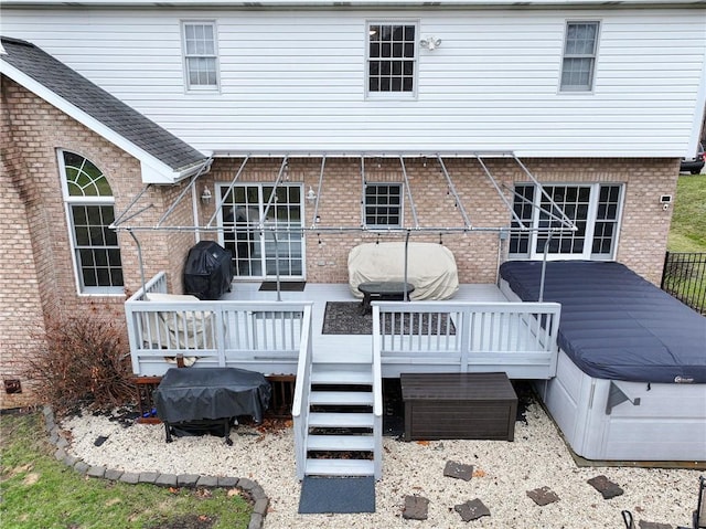 rear view of house with a hot tub and a deck