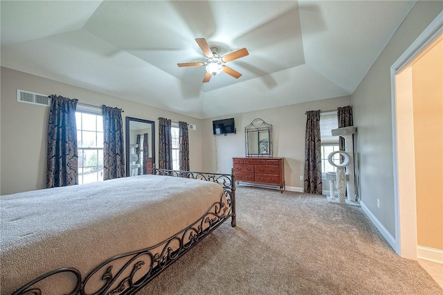 bedroom featuring ceiling fan, a tray ceiling, and light carpet