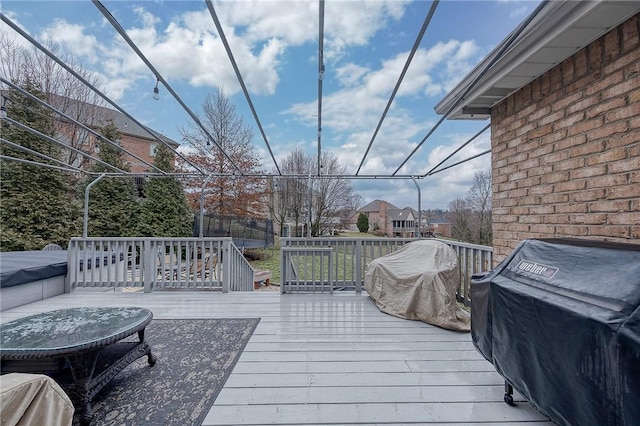 wooden terrace with area for grilling and a trampoline