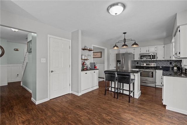 kitchen featuring appliances with stainless steel finishes, white cabinetry, a kitchen breakfast bar, dark hardwood / wood-style floors, and a center island