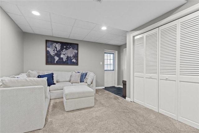 carpeted living room featuring a drop ceiling