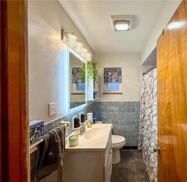 bathroom featuring vanity, tile walls, and toilet