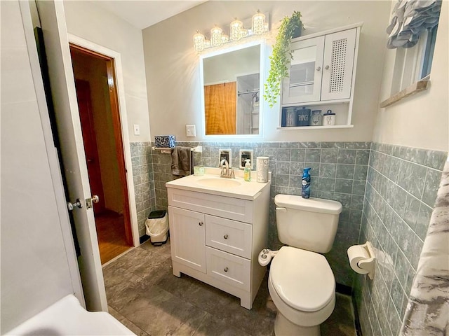 bathroom with vanity, tile walls, and toilet