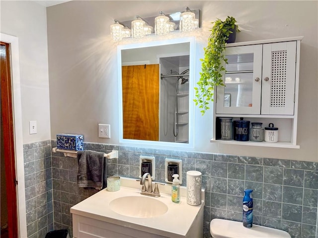 bathroom with tile walls, vanity, toilet, and walk in shower