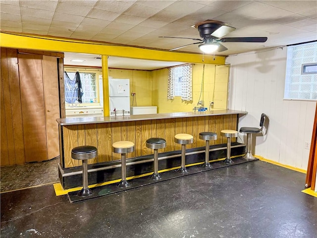 bar featuring white refrigerator, ceiling fan, and plenty of natural light