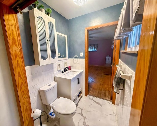 bathroom featuring vanity, tile walls, and toilet