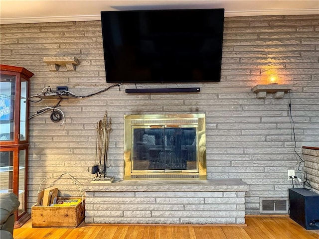 interior details with crown molding, wood-type flooring, and a fireplace