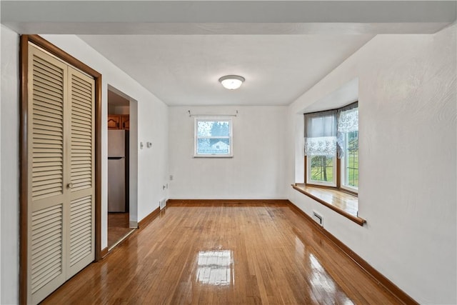 unfurnished bedroom with stainless steel fridge, light hardwood / wood-style floors, and a closet