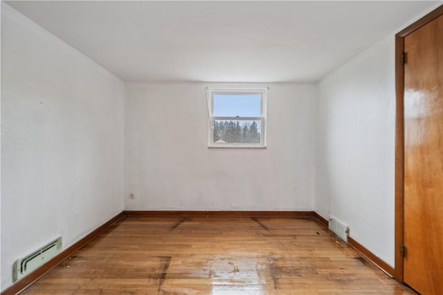 unfurnished room featuring light wood-type flooring and baseboard heating