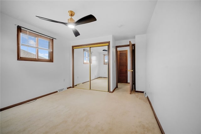 unfurnished bedroom with light colored carpet, a closet, and ceiling fan