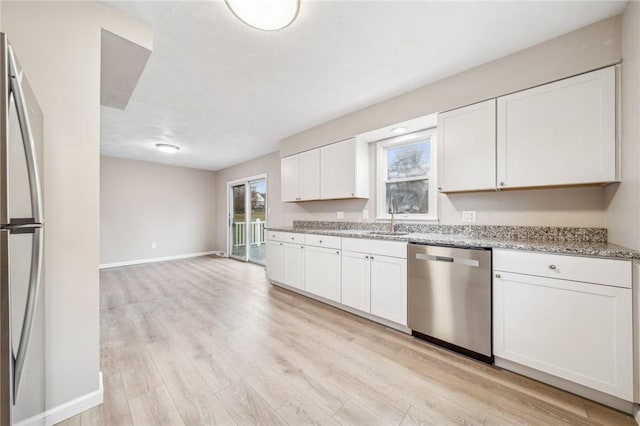 kitchen with appliances with stainless steel finishes, light stone countertops, light hardwood / wood-style flooring, and white cabinets