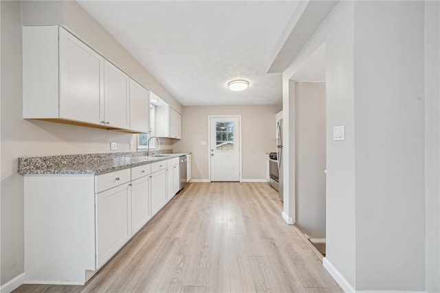 kitchen with light stone counters, stainless steel dishwasher, range, and white cabinets