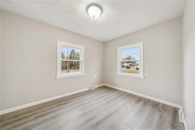 empty room with plenty of natural light and light hardwood / wood-style floors