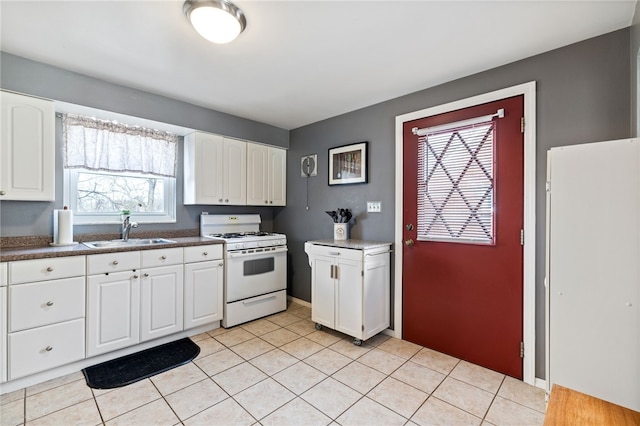 kitchen with white cabinetry, sink, white gas stove, and light tile patterned floors