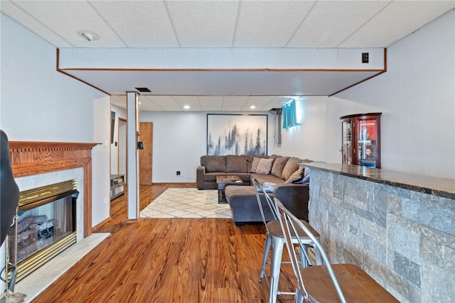 living room featuring a drop ceiling and light wood-type flooring