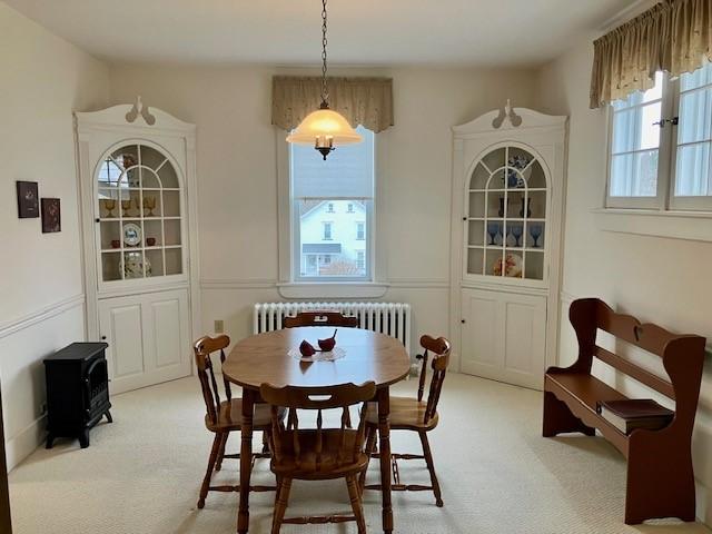 dining area with light carpet and radiator