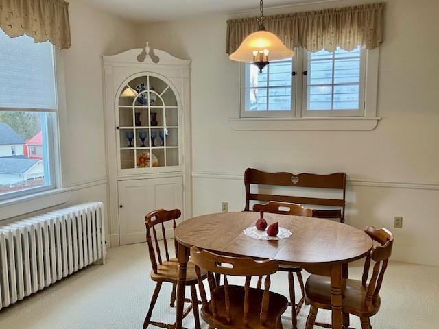 carpeted dining space with radiator heating unit