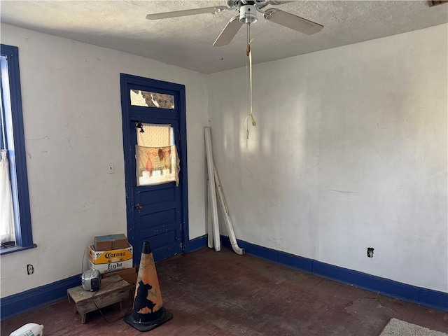 empty room with ceiling fan and a textured ceiling