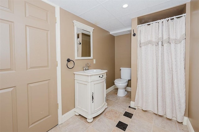 bathroom with a paneled ceiling, vanity, toilet, and tile patterned floors