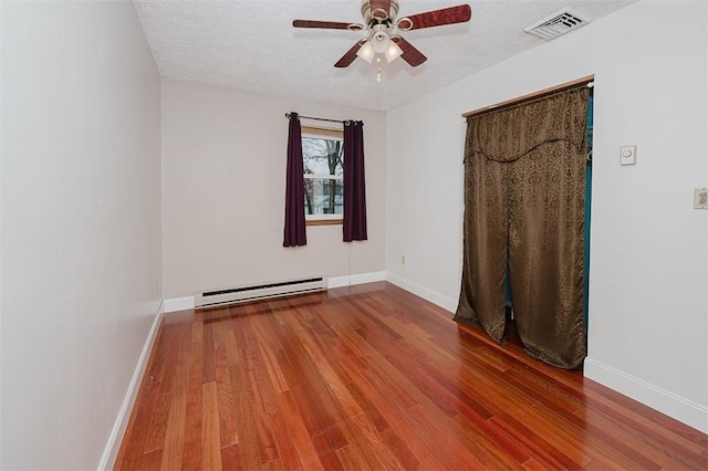 unfurnished room featuring baseboard heating, ceiling fan, wood-type flooring, and a textured ceiling