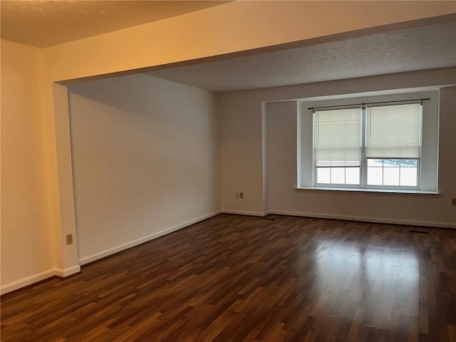 empty room featuring dark hardwood / wood-style floors and a textured ceiling