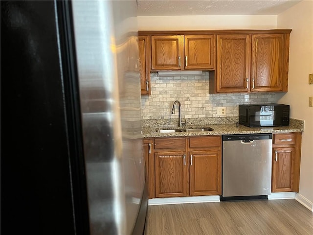 kitchen featuring sink, appliances with stainless steel finishes, dark hardwood / wood-style floors, light stone countertops, and decorative backsplash