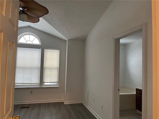 empty room with dark wood-type flooring, lofted ceiling, and a textured ceiling