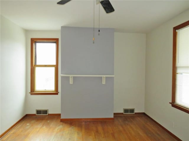 spare room featuring hardwood / wood-style flooring, a healthy amount of sunlight, and ceiling fan