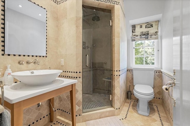 bathroom featuring tile patterned floors, toilet, sink, tile walls, and a shower with door