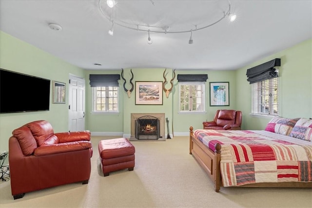 bedroom featuring track lighting, light carpet, and multiple windows