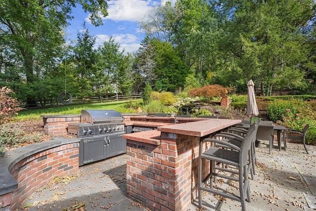 view of patio with a bar, an outdoor kitchen, and area for grilling