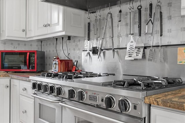 kitchen featuring white cabinetry, range with two ovens, and decorative backsplash