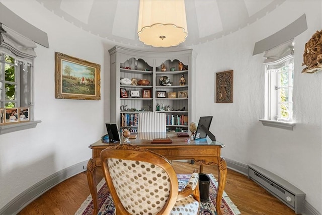 office area with a baseboard heating unit and wood-type flooring