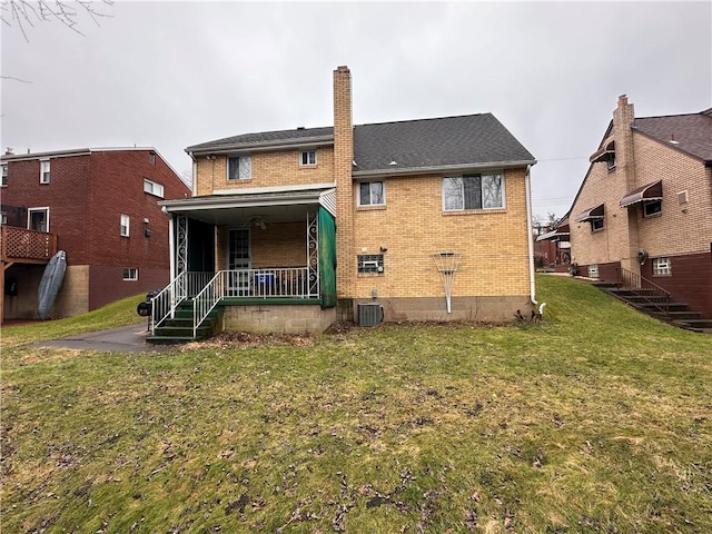 rear view of property featuring cooling unit, covered porch, and a lawn