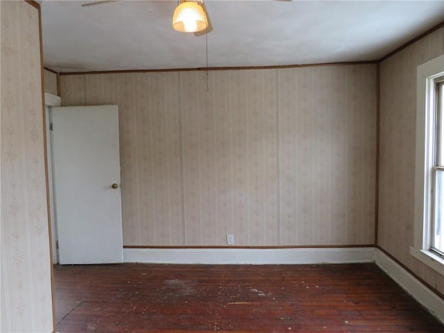 empty room featuring wallpapered walls, baseboards, and hardwood / wood-style floors