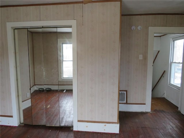 unfurnished room with wood-type flooring, visible vents, and baseboards