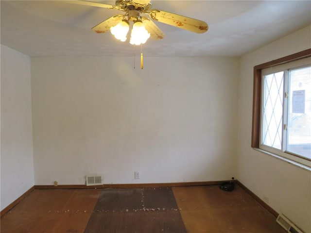 spare room with a ceiling fan, wood finished floors, visible vents, and baseboards